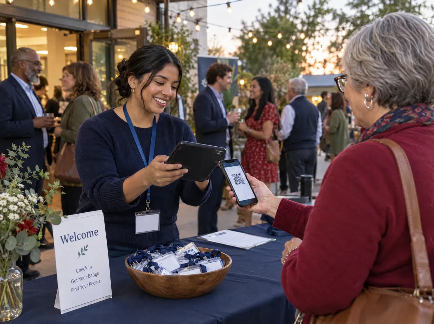 A volunteer at a welcome table scanning the QR code on a guest's phone as she arrives